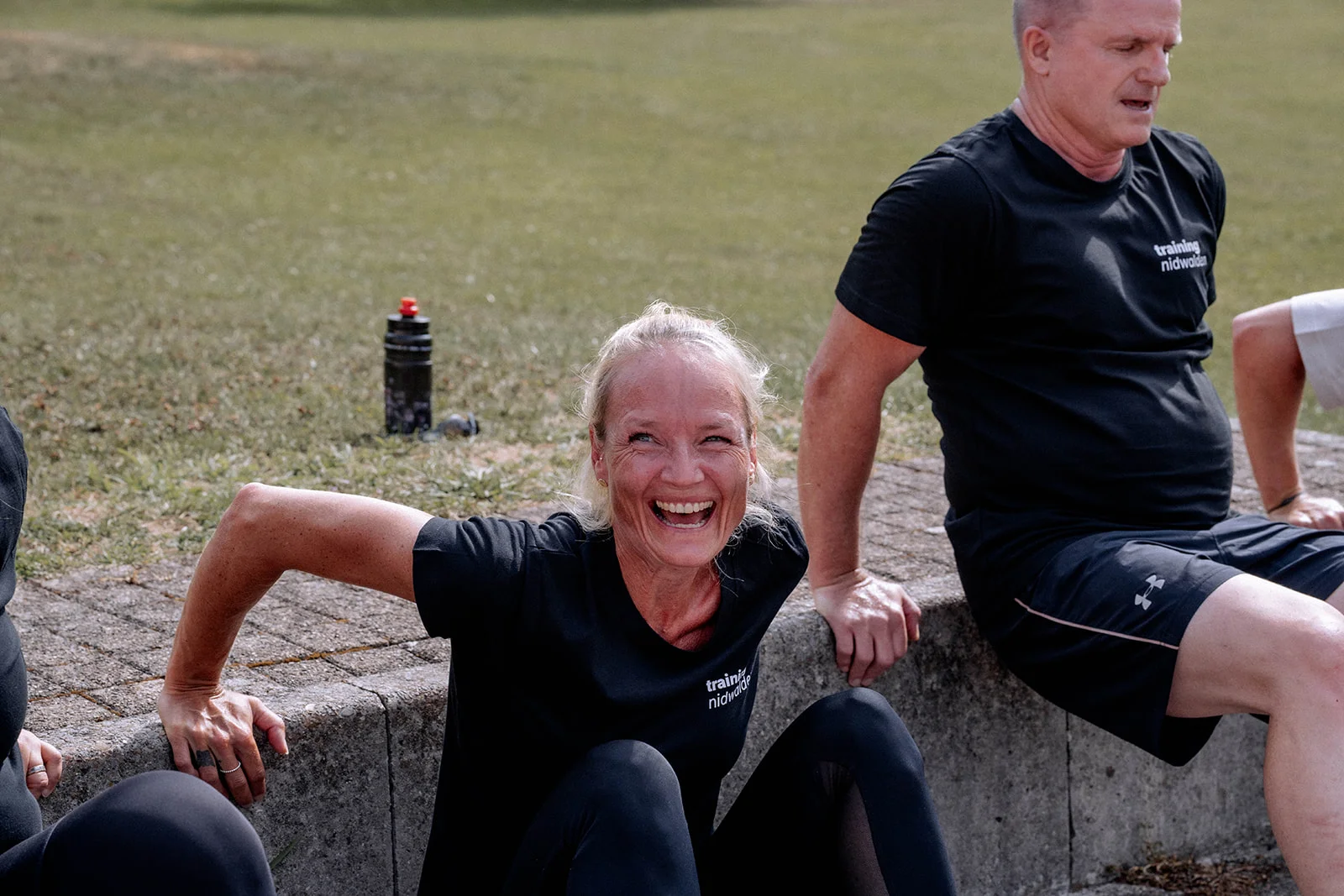 Fabienne lacht während einer Übung auf der Mauer, ein Teilnehmer daneben